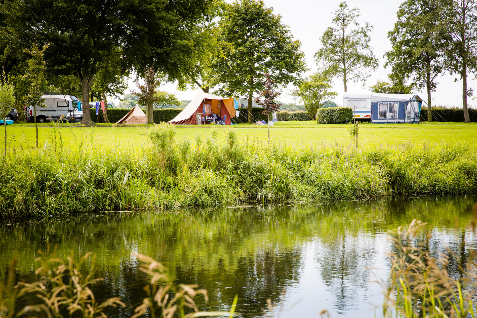 Op deze foto zie je caravans en tenten staan aan de rivier de Berkel in Almen. Camping Domein Groot Besselink.